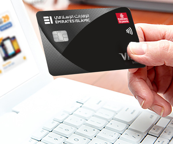 Person holding a credit card in front of a laptop