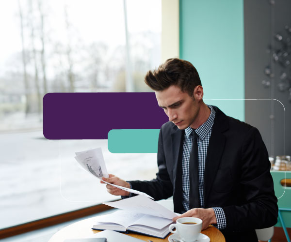 نرى شخصاً يقوم بمراجعة مستندات مالية في المقهى.